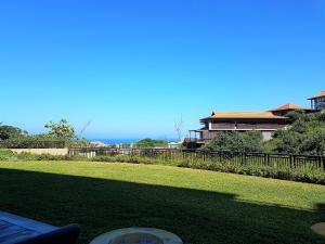 a field of grass with a fence and a building at Zimbali Suites 106 in Ballito
