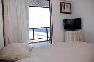 um quarto com uma cama, uma TV e uma janela em Apartamento Varandas Barra Flat no Rio de Janeiro