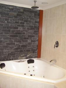 a bath tub sitting next to a wall in a bathroom at Koala Tree Motel in Port Macquarie