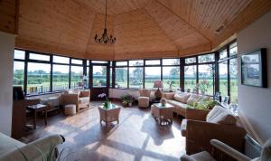 uma ampla sala de estar com sofás, mesas e janelas em Browns Country House em Bushmills