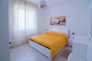 a white bedroom with a bed with a yellow blanket at Silky House with Private Parking in Como