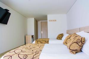 a bedroom with two beds and a flat screen tv at Hotel Arawak Plaza in Sincelejo