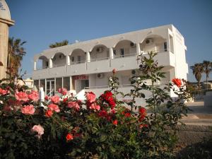 a white building with red flowers in front of it at Antonis Hotel in Kefalos