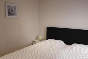 a bedroom with a white bed with a black headboard at De Lanterfanters Vakantiehuis Jef in Nieuwpoort +24 photos