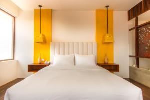 a bedroom with a large white bed with yellow walls at Apsara Residence Hotel in Siem Reap