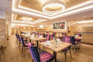 jadalnia z drewnianymi stołami i fioletowymi krzesłami w obiekcie Hotel Flachauerhof w mieście Flachau