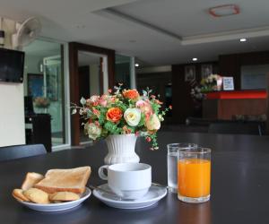 Airport Resident في شيانغ ماي: طاولة مع مزهرية مع باقة من الزهور والخبز المحمص