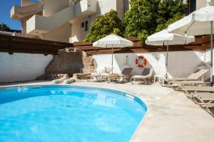 basen z leżakami i parasolami obok budynku w obiekcie Alecos Hotel Apartments w Pafos