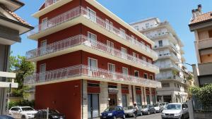 a red building with white balconies on a street at Majestic Suite in San Benedetto del Tronto