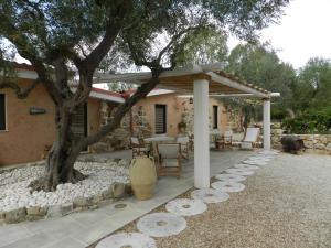 a patio with a tree and a table and chairs at Macchia Salentina in Baia Di Gallipoli