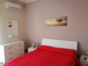 a bedroom with a bed with a red blanket at Appartamento Villarosa in Syracuse