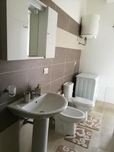 a bathroom with a sink and a toilet and a mirror at Appartamento Villarosa in Syracuse