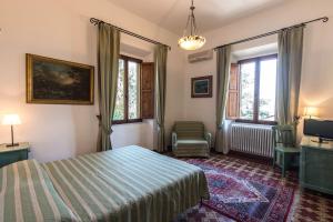 a bedroom with a bed and a chair and windows at Hotel Villa Porta All'Arco in Volterra