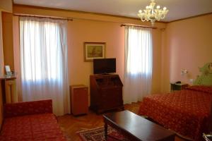 a living room with a bed and a tv and curtains at Hotel Malibran in Venice