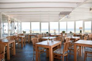 a restaurant with wooden tables and chairs and windows at Strandhotel Noordzee in De Koog