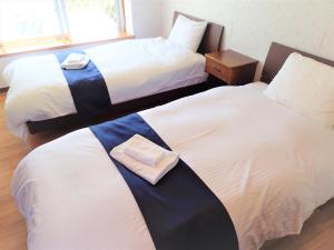 a hotel room with two beds with towels on them at Seaside KLATCH -Villa&sauna- in Ishigaki Island