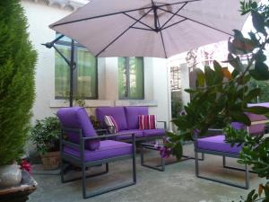 eine Terrasse mit lila Stühlen und einem Sonnenschirm in der Unterkunft La Pergola in Châteauneuf-du-Pape