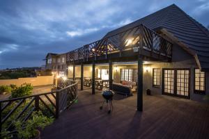 a house with a large deck with a grill at Khaya La Manzi Guest Lodge in Hibberdene