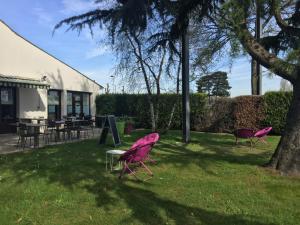 two pink chairs sitting in the grass in a yard at Campanile Nantes ~ Saint-Herblain in Saint-Herblain