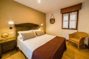 a bedroom with a large bed and a chair at Apartamentos Las Fuentes in Llanes