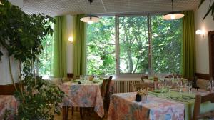 a restaurant with tables and chairs and a large window at Logis Le Ceans in Orpierre