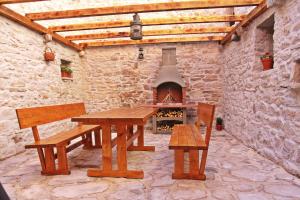 a picnic table and benches in a stone building with a fireplace at Apartmani Strada in Kaštela