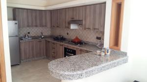 a kitchen with a granite counter top and a refrigerator at Villa Marina à Savannah Beach sidi rahal in Sidi Rahal