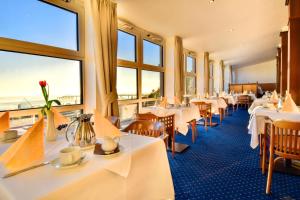 um restaurante com mesas, cadeiras e janelas em Promenadenhotel Admiral em Bansin