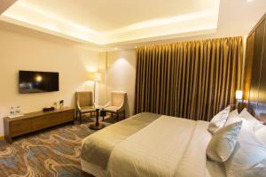 a hotel room with a bed and a desk and chair at Golden Tulip The Grandmark Dhaka in Dhaka