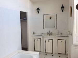 W białej łazience znajduje się umywalka i lustro. w obiekcie Hotel des Tailles w mieście Mortagne-au-Perche