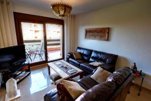 sala de estar con sofá de cuero y TV en Apartamentomirada en Estepona