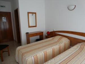 a bedroom with two beds and a table and a mirror at Hospedaria Descansa Pernas in Monchique