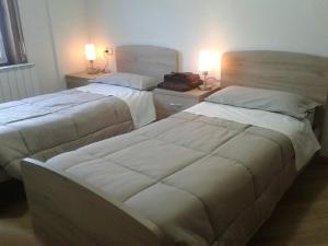 two beds in a hotel room with two lamps at Casa Debora in Valdidentro