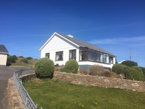 a white house with a stone wall at Hillcrest Holiday Home in Cruit