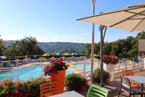 Blick auf den Pool in einem Hotel mit Tischen und Stühlen in der Unterkunft VVF Aveyron Najac in Najac