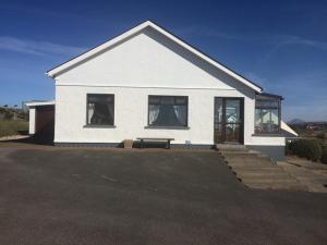 a white house with a bench in front of it at Hillcrest Holiday Home in Cruit