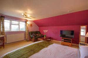 a bedroom with purple walls and a bed and a tv at Mount Lavinia in Sheringham