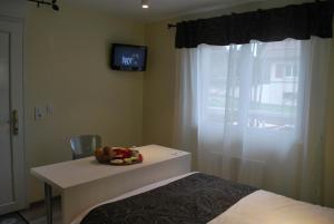 a room with a bed and a table and a television at Hôtel Les Perce-Neige in Bonnétage