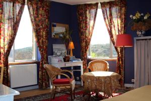 ein Wohnzimmer mit blauen Wänden und Fenstern sowie einem Tisch und Stühlen in der Unterkunft chambres d'hotes du Manoir de Suguensou in Audierne