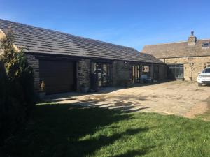 een gebouw met een garage en een auto ernaast bij The Coach House & The Stables Holiday Homes Windy Bank Hall Green Moor Yorkshire Peak District in Wortley