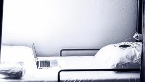 laptopa siedzącego na łóżku w obiekcie ODA Hostel w Prisztinie