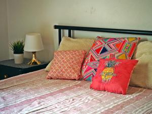 a bed with colorful pillows and a lamp on a table at Ema's Beach and Nightlife House in Lagos