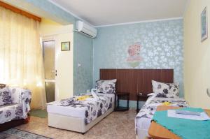 a bedroom with two beds and a chair and a table at Violeta 7 Guest House in Nesebar