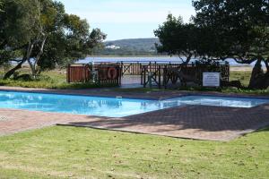una piscina con parque infantil, árboles y agua en Keurbooms River Lodge 1311 en Plettenberg Bay