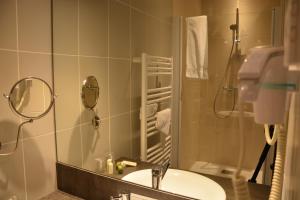 a bathroom with a sink and a shower with a mirror at Logis Le Ceans in Orpierre