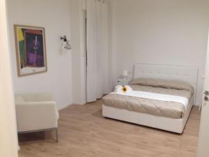 a white bedroom with a bed and a chair at Dante 58 in Palermo