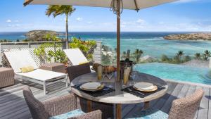 a patio with a table and chairs and the ocean at Villa Lodge 4 Epices in Gustavia