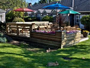 a garden with a table and chairs and umbrellas at Ecola Creek Lodge in Cannon Beach
