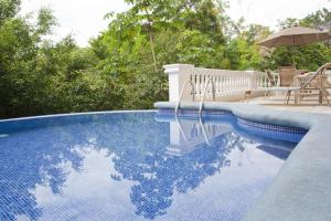 a swimming pool with a table and an umbrella at Pacifico Colonial Condominiums in Manuel Antonio