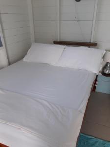 Bett in einem Zimmer mit weißer Bettwäsche und Kissen in der Unterkunft Cosy Hut in Saint Georgeʼs